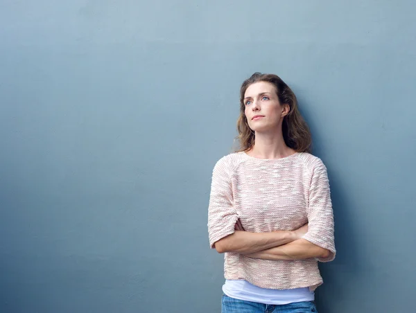 Woman with arms crossed looking away with thoughtful expression — Stock Photo, Image