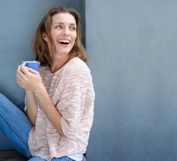 Счастливая женщина смеется с чашкой кофе в руке — стоковое фото