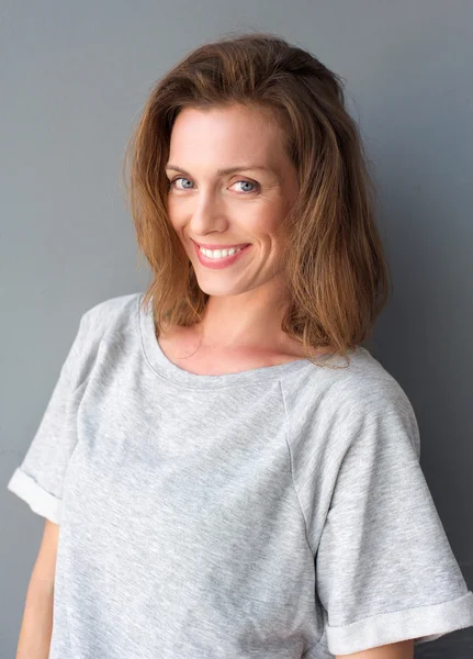 Portrait of a beautiful mid adult woman smiling on gray background — Stock Photo, Image