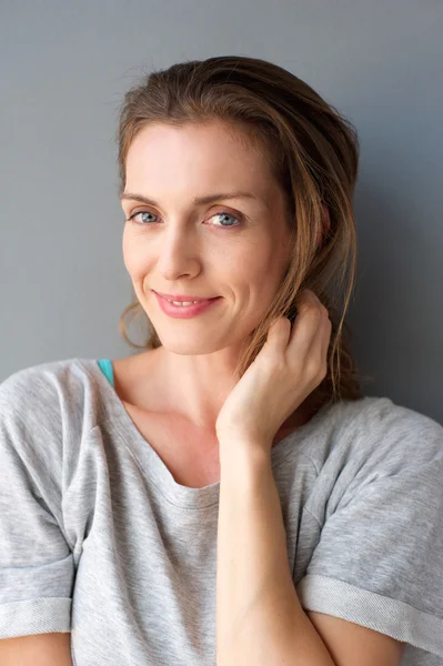 Lovely mid adult woman smiling with hand in hair — Stock Photo, Image