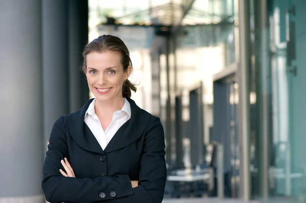 Confident business woman smiling with arms crossed — Stock Photo, Image