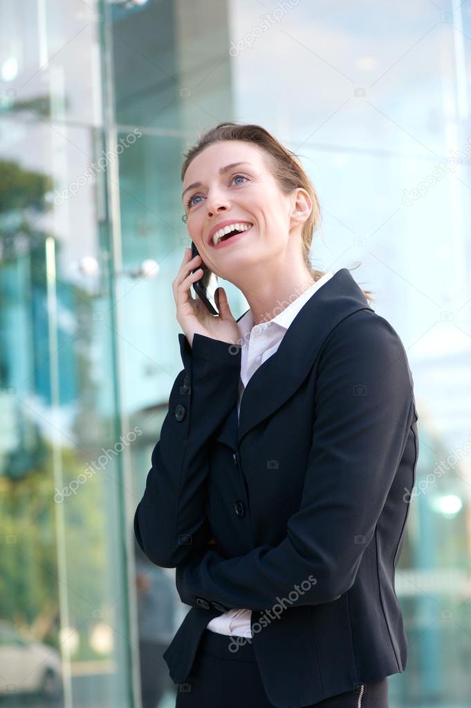 Happy business woman walking and talking on cellphone