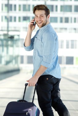 Cep telefonu ve paket ile yürüyen genç erkek Gezgin
