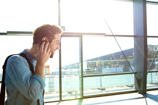 Leende ung man ringa med mobiltelefon vid stationen — Stockfoto