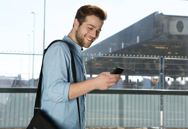 Happy modern man sending text message at airport — Stock Photo, Image