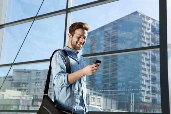 Aantrekkelijke jonge man lopen en kijken naar mobiele telefoon — Stockfoto