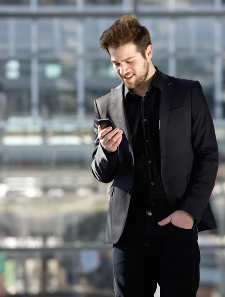 Bello giovanotto guardando il messaggio di testo del telefono cellulare — Foto Stock
