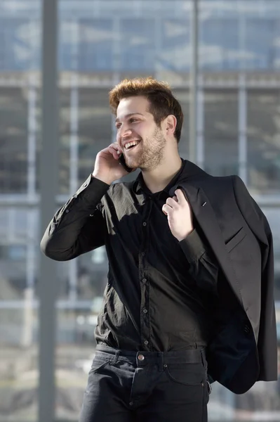 Νεαρός άνδρας, χαμογελώντας με το κινητό στην πόλη — Φωτογραφία Αρχείου