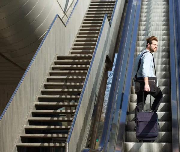 Bonito homem caminhando escada rolante com sacos de viagem — Fotografia de Stock