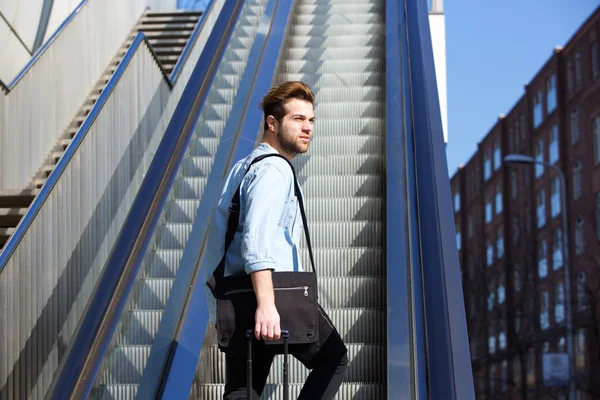 Chico joven con bolsas caminando por escaleras mecánicas — Foto de Stock