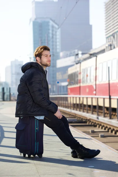 Attraktiv ung man sitter och väntar på tåget vid stationen — Stockfoto