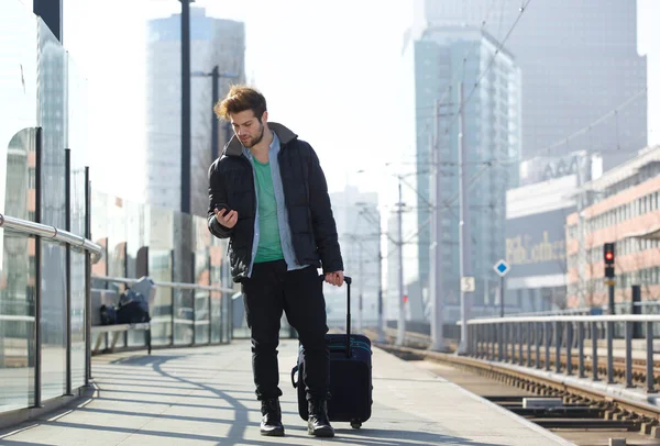 Молодой человек путешествует с сумкой и мобильным телефоном — стоковое фото