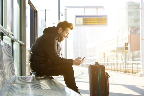 Giovane sorridente con cellulare e borsa — Foto Stock