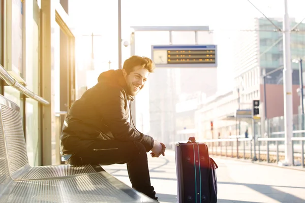Šťastný mladý muž čeká na vlak na stanici s taškou — Stock fotografie