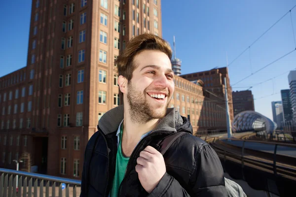 Šťastný mladý muž v městě s taškou — Stock fotografie