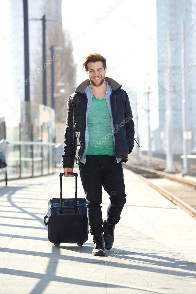 Happy man walking on train station platform with bag