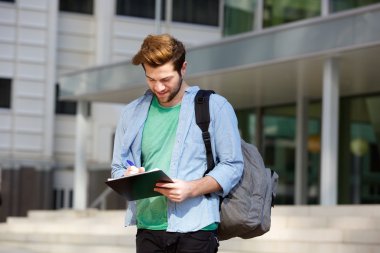 Not defteri ve paket ile ayakta dışında erkek üniversite öğrencisi