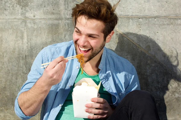Homem feliz comendo comida com pauzinhos — Fotografia de Stock