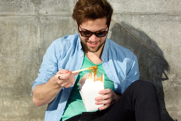 Homem relaxante e comer comida asiática com pauzinhos — Fotografia de Stock