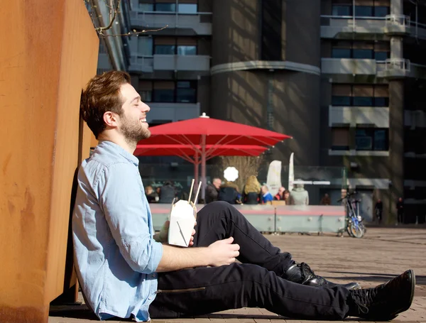 Hombre feliz relajándose al aire libre con comida china para llevar — Foto de Stock