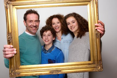 Resim çerçevesi tutarak ve gülümseyerek mutlu bir aile
