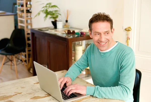 Gelukkig midden oude mens met behulp van laptop thuis — Stockfoto