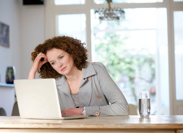 Attraktiv äldre kvinna tittar på laptop hemma — Stockfoto