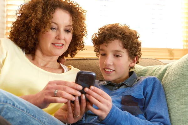 Feliz madre e hijo sentados en el sofá en casa — Foto de Stock