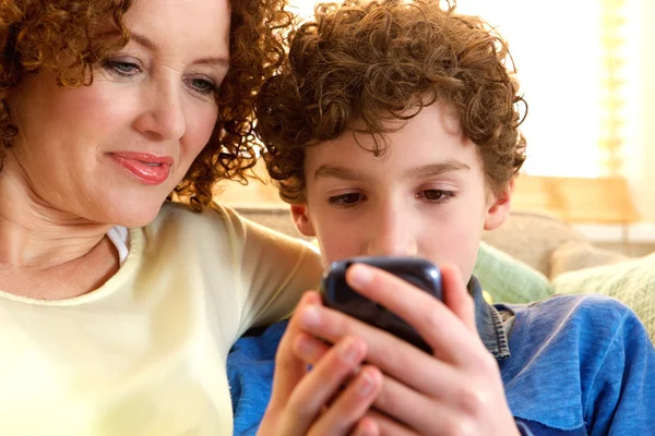 Feliz madre e hijo mirando el dispositivo móvil — Foto de Stock