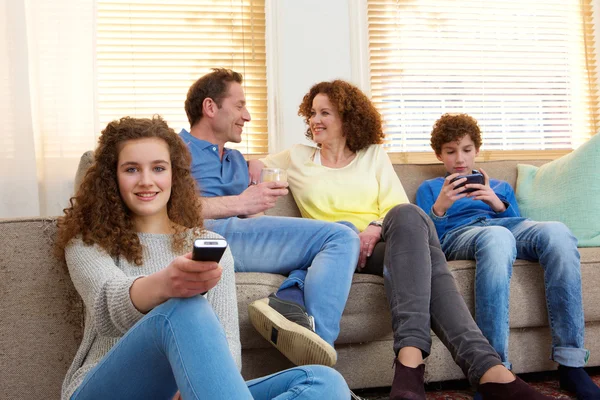 Glad familie sidder derhjemme afslappende i stuen - Stock-foto