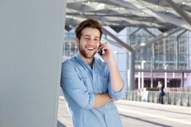 Cep telefonuyla konuşurken yakışıklı genç gülümseyen