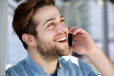 Genç gülümseyen ve cep telefonuyla konuşan adam
