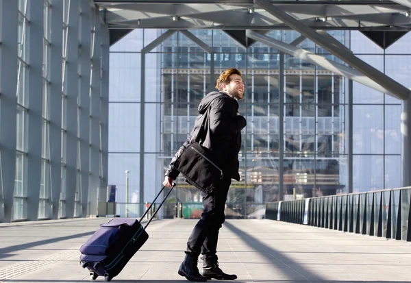 Glad ung man gå med resväska på station — Stockfoto