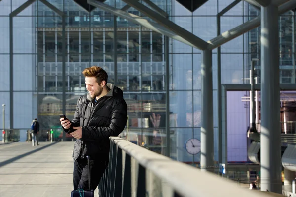 Homme heureux attendant à la gare et regardant le téléphone mobile — Photo
