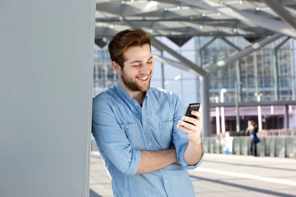 Smiling man reading text message on mobile phone — Stock Photo, Image