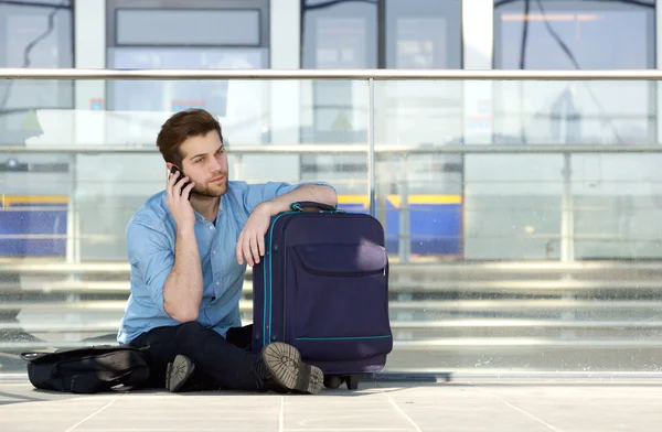 Manlig resenär sitter på golvet talar i mobiltelefon — Stockfoto