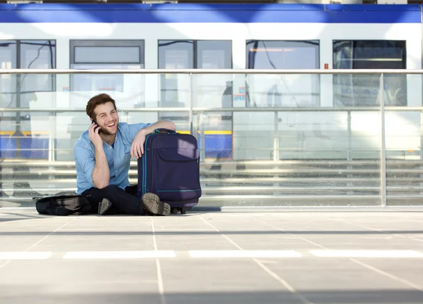 Uomo seduto sul pavimento con borsa e parlando sul cellulare — Foto Stock