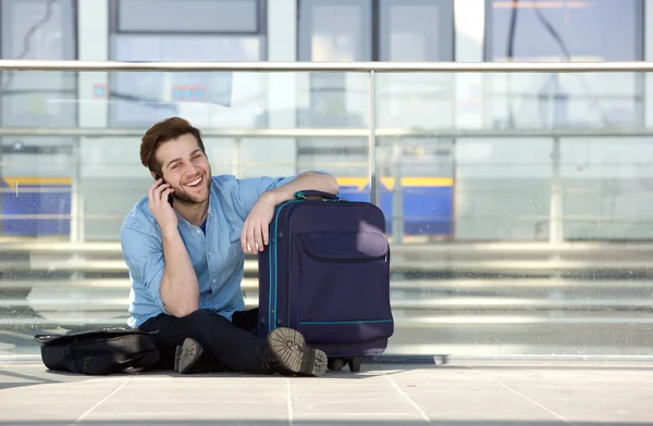 Zufriedene Reisende, die am Bahnhof warten und mit dem Handy telefonieren — Stockfoto