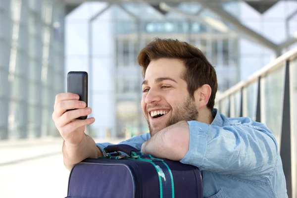 Jovem feliz com saco de viagem olhando para o telefone celular — Fotografia de Stock