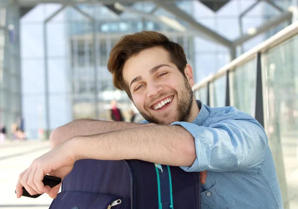 Příjemný mladý muž relaxační na stanici s taškou — Stock fotografie