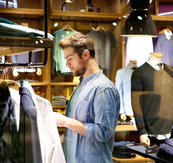 Mandsome jovem comprando roupas na loja — Fotografia de Stock