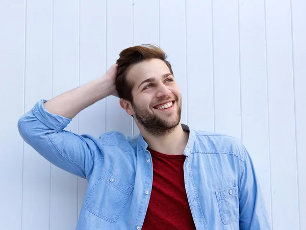 Fröhlicher junger Mann lächelt mit der Hand im Haar — Stockfoto