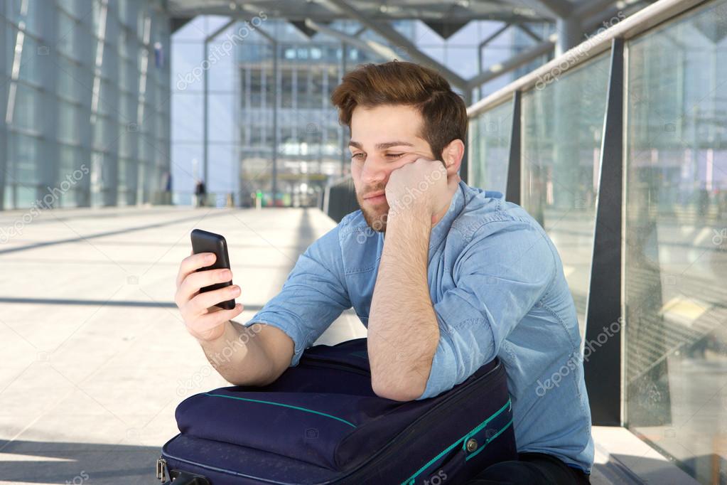 Man waiting at airport with bored expression on face