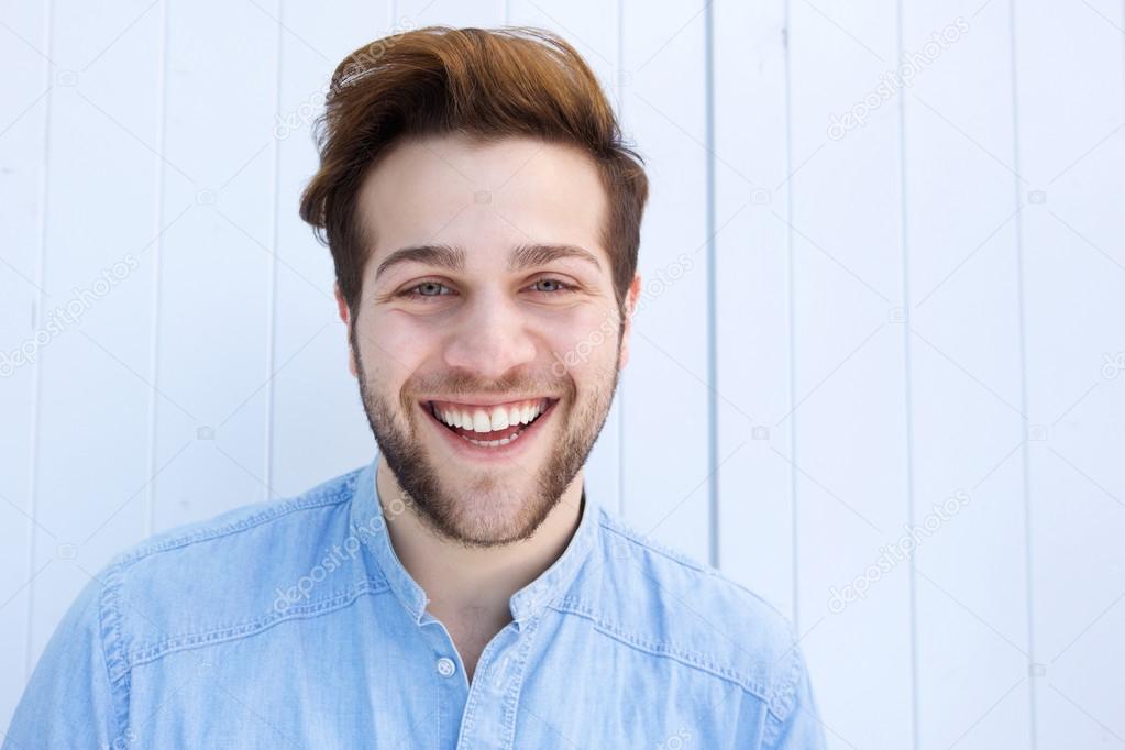 Cheerful young man laughing against white background