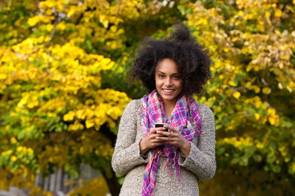 Sonriente mujer joven sosteniendo el teléfono móvil al aire libre —  Fotos de Stock