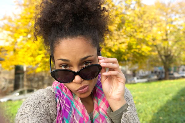 Mujer joven mirando por encima de las gafas de sol — Foto de Stock