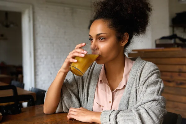 Young mixed race woman drinking orange juice — Stock Photo, Image