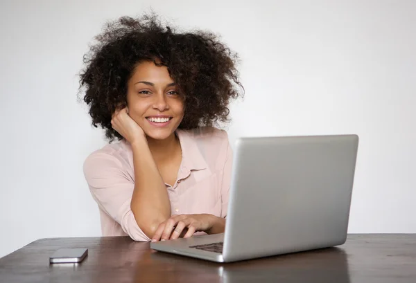 Усміхнена молода жінка сидить за столом з ноутбуком — стокове фото