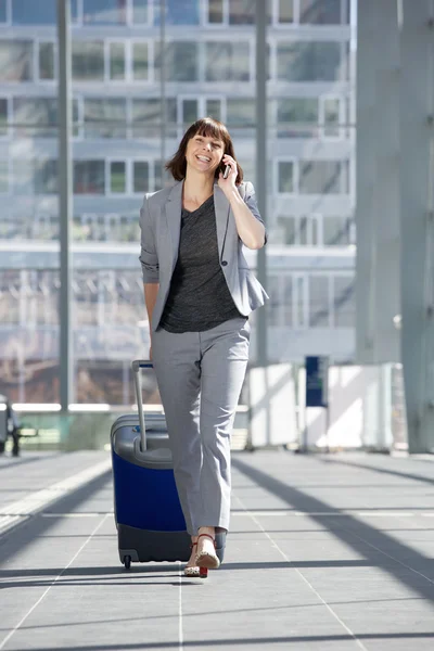 Boldog üzleti nő beszél a mozgatható telefon-nél repülőtér — Stock Fotó