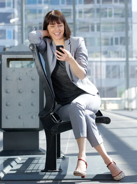 Sorrindo mulher de negócios lendo mensagem de texto no telefone móvel — Fotografia de Stock